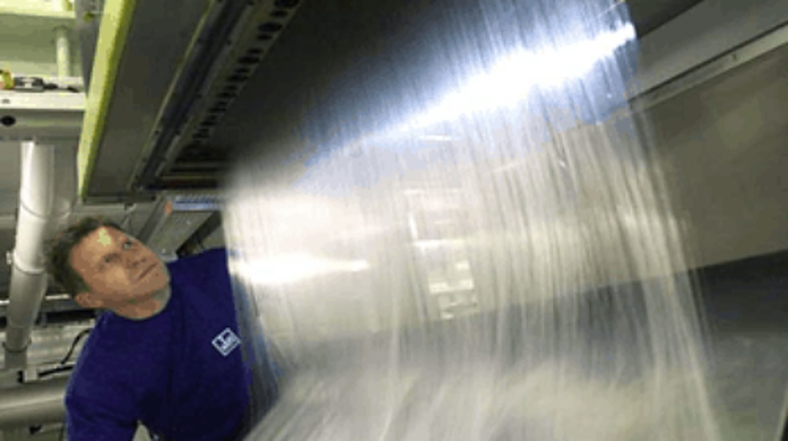 Técnico observando la cinta de malla tejida de una línea de spunbond durante la limpieza con hielo seco