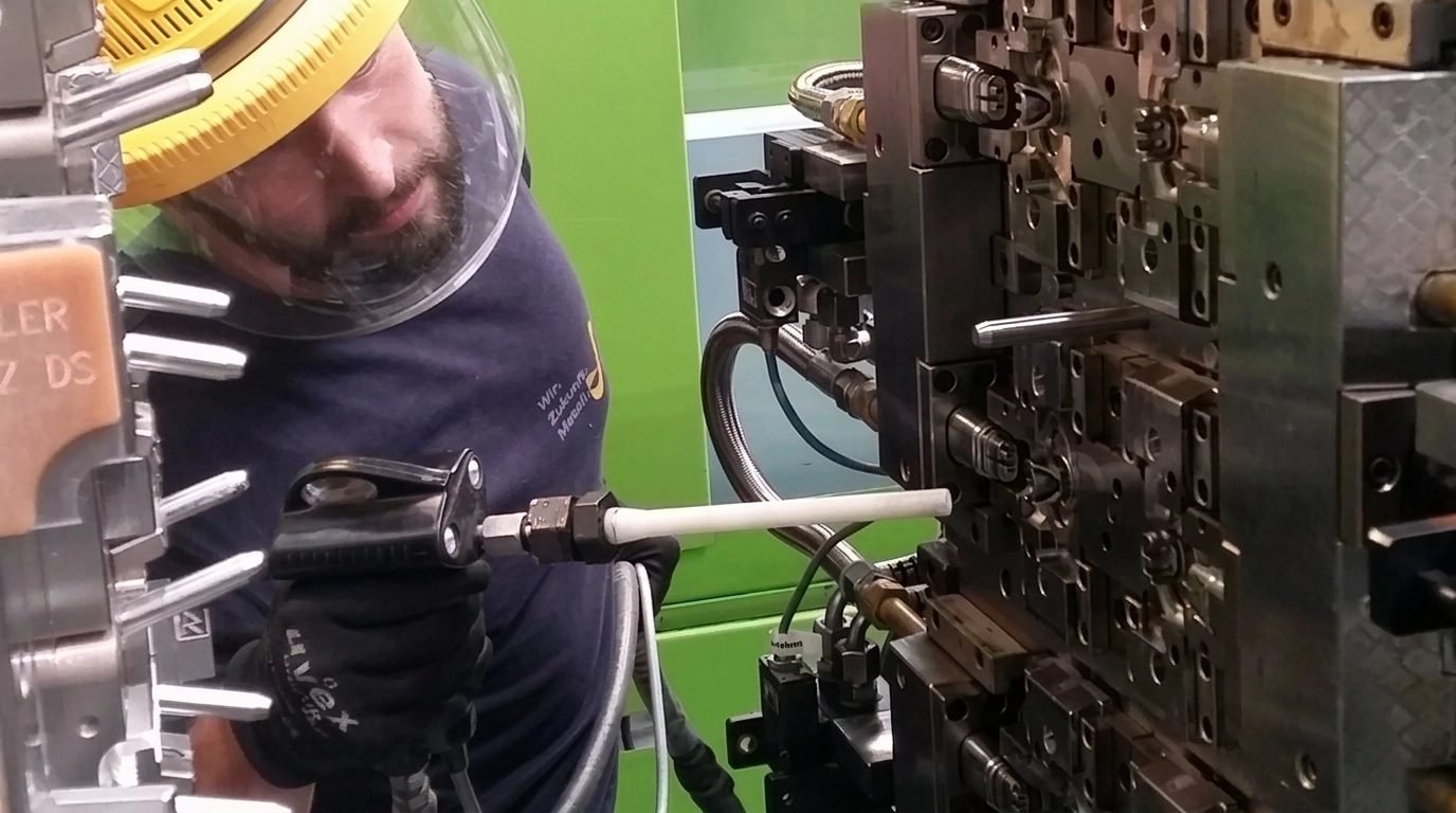 Operario limpiando con hielo seco un molde de inyección de plástico en la máquina con una pistola Cold Jet