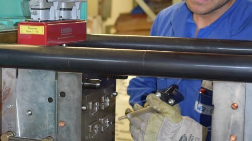 Operario trabajando en un molde de inyección de plástico montado en la máquina de moldeo